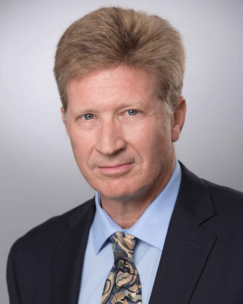 Male creative headshot with urban alley background.
